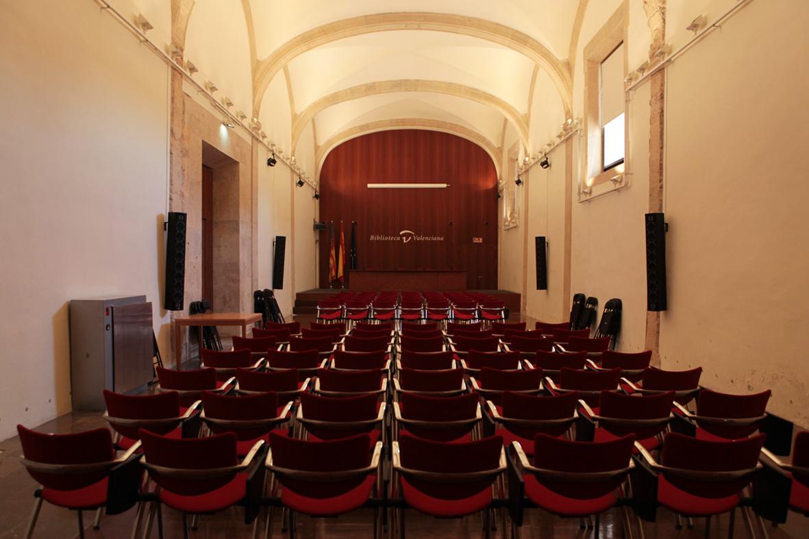 Salón preparado para acto o evento institucional con disposición de butacas y escenario